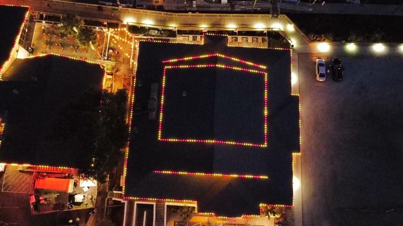 Aerial view of a restaurant roofline outlined in warm white lights