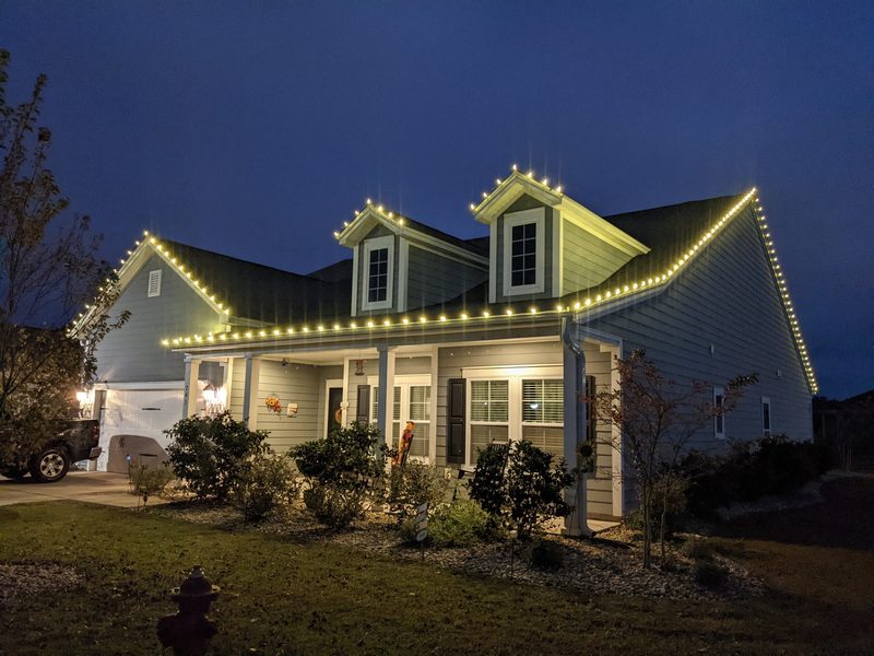Ranch home with warm white roofline and dormer lights at dusk
